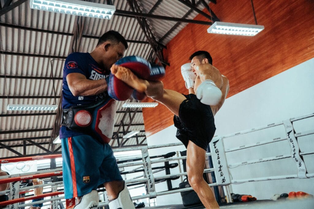 pexels-photo-2628210-2628210 Two fighters engage in a dynamic Muay Thai training session inside a gym.