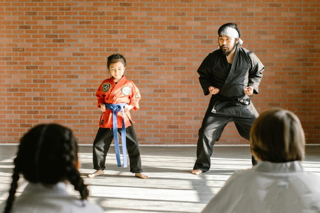 pexels-photo-7045561-7045561 A martial arts instructor and a child student practicing karate in a dojo.