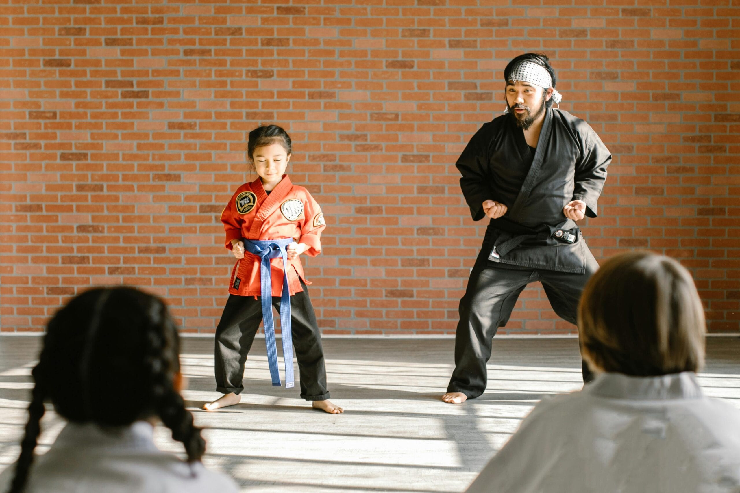 A martial arts instructor and a child student practicing karate in a dojo.
