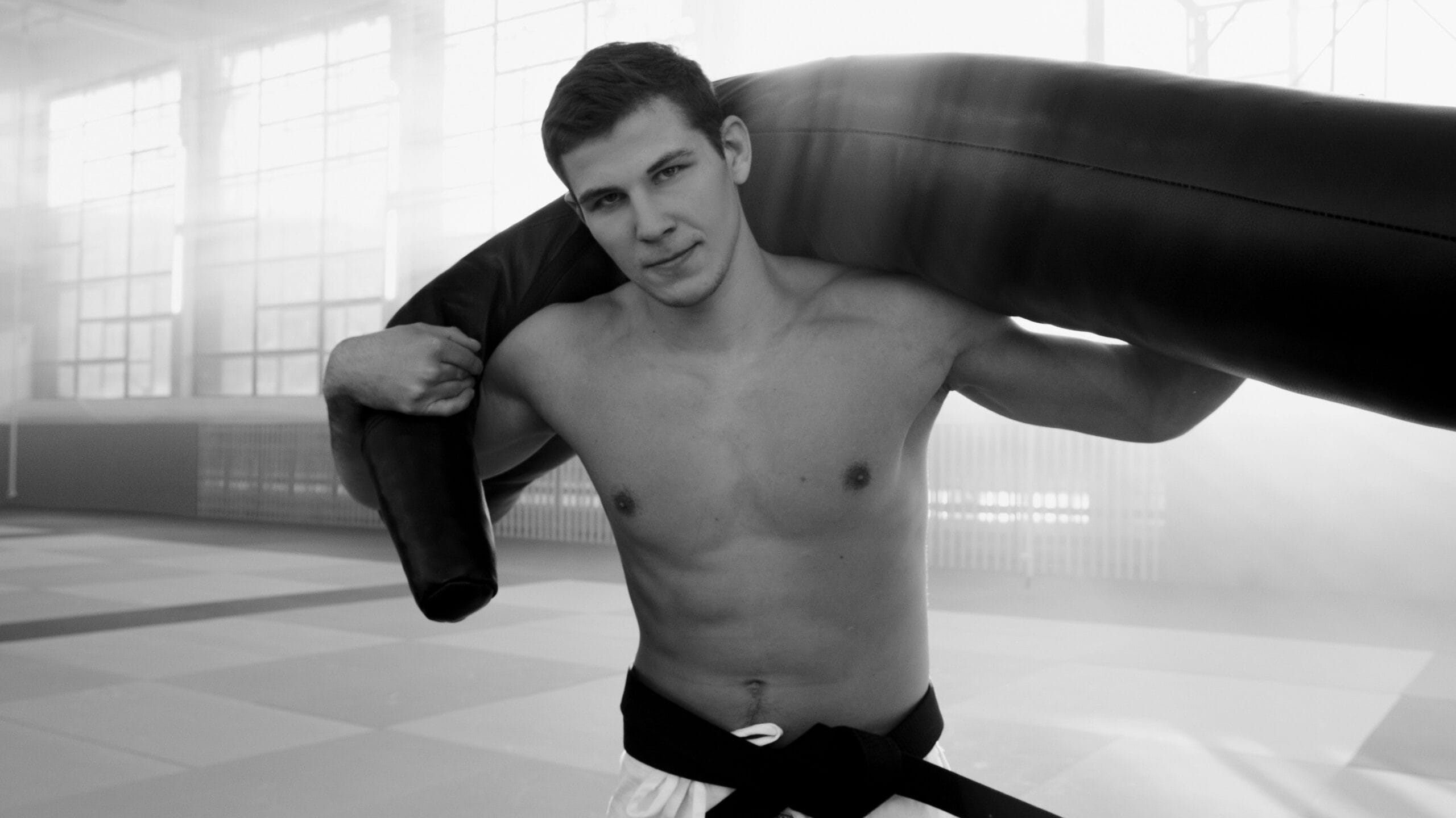 A young male martial artist training indoors with a punching bag.